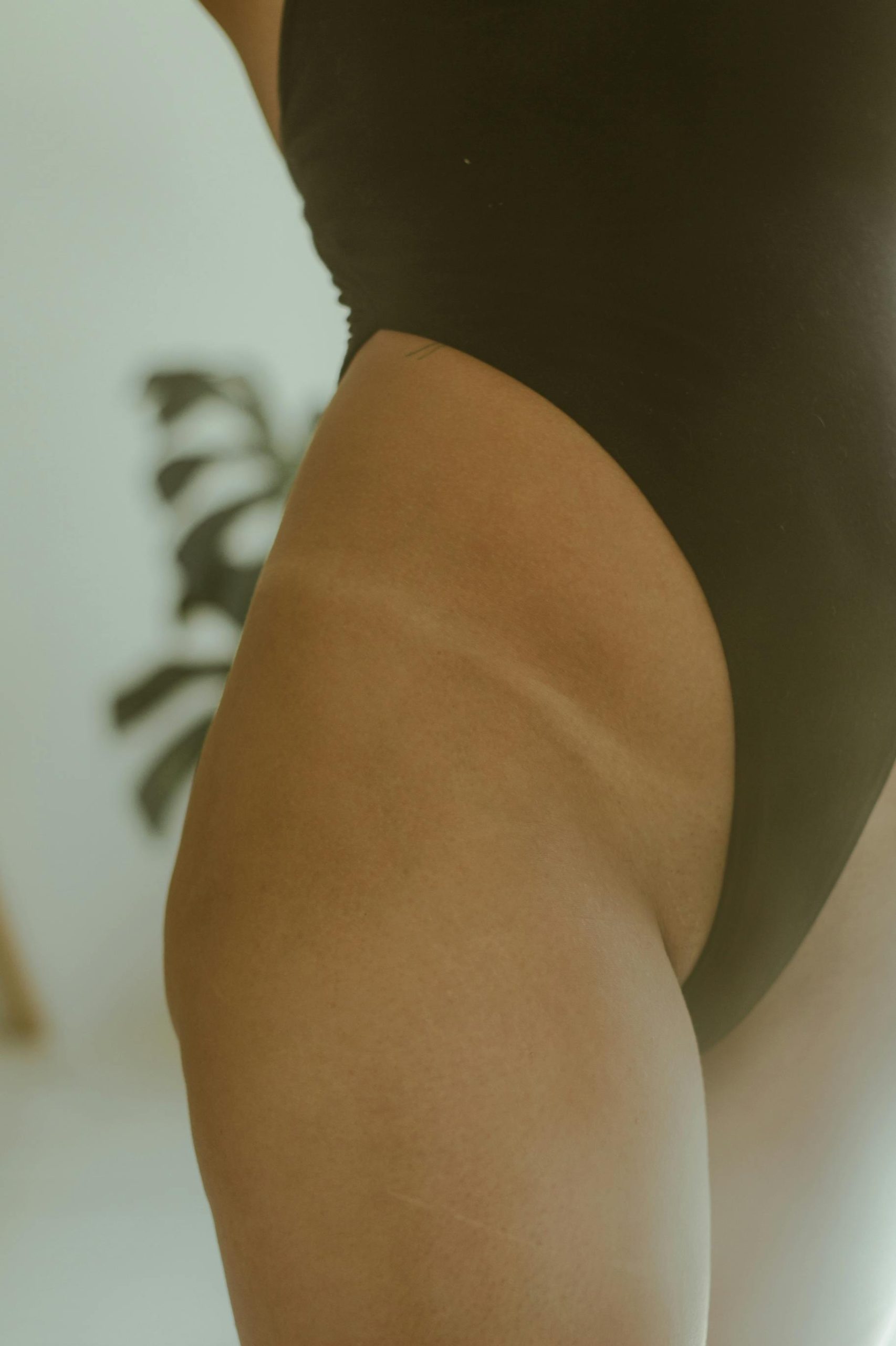 Elegant close-up of a woman's tan line in a black swimsuit, highlighting skin texture and tone.